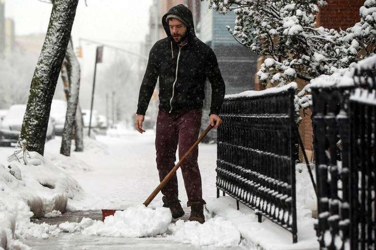 Homem limpa neve em calçada de Nova York. 05/03/2015