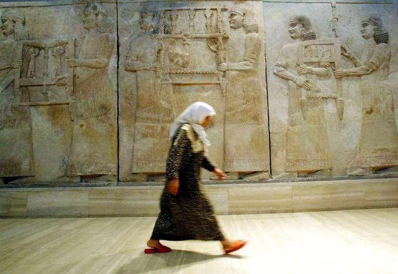Iraquiana passa por mural assírio em museu de Bagdá retirado da cidade de Nimrud, em foto de arquivo. 03/07/2003