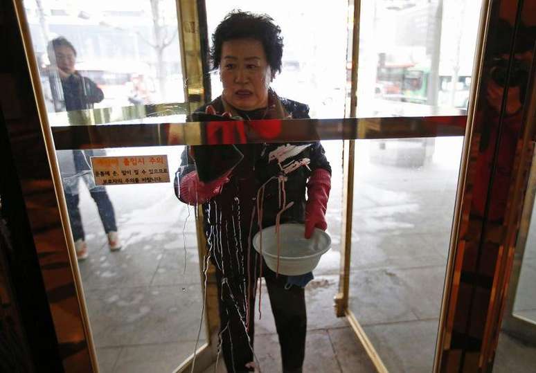 <p>Mulher limpa manchas de sangue em local de ataque contra embaixador dos EUA em Seul, na Coreia do Sul</p>