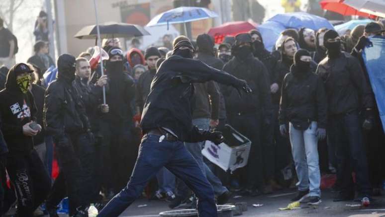 <p>Manifestante joga pedras em policiais em frente a sede do BCE, em Frankfurt</p>