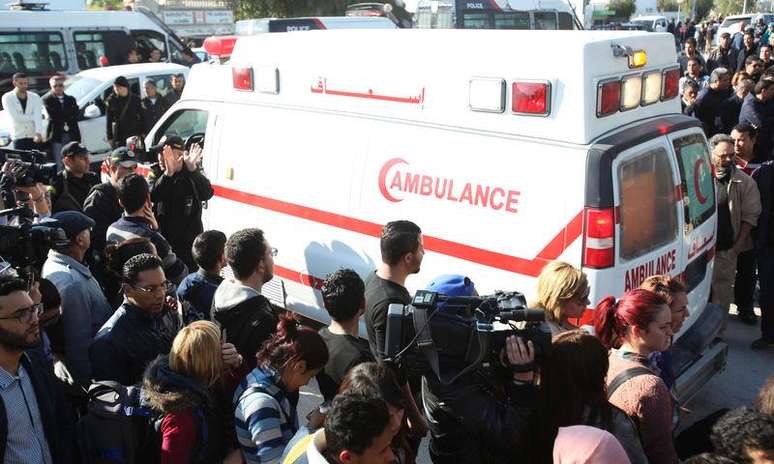 <p>Pessoas em volta de uma ambulância que transporta os corpos das vítimas do ataque em Túnis</p>