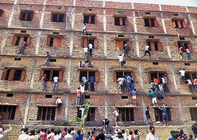 Indianos escalam prédio em que estudantes fazem uma prova em Hajipur, no leste do estado de Bihar