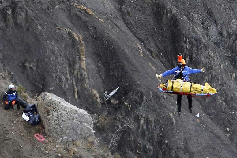 <p>Socorrista é içado por um helicóptero após coletar destroços da aeronave da Germanwings e restos mortais das vítimas nos alpes franceses</p>