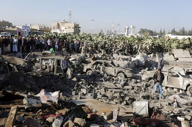 Pessoas cercam área alvo de um ataque aéreo nos arredores do aeroporto de Sanaa