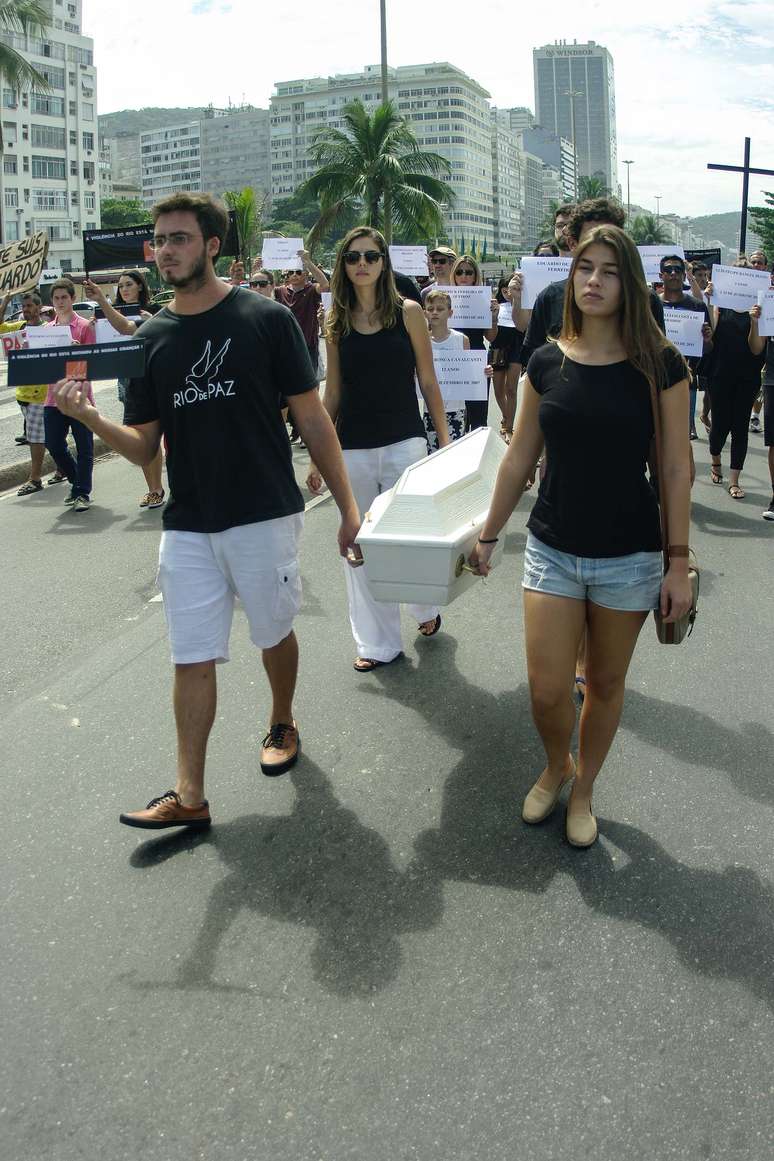 <p>Manifestantes carregando um caixão percorreram a Avenida Atlântica antes de realizar um enterro simbólico, deixando na areia uma cruz de madeira em homenagem a Eduardo e às outras vítimas</p>
