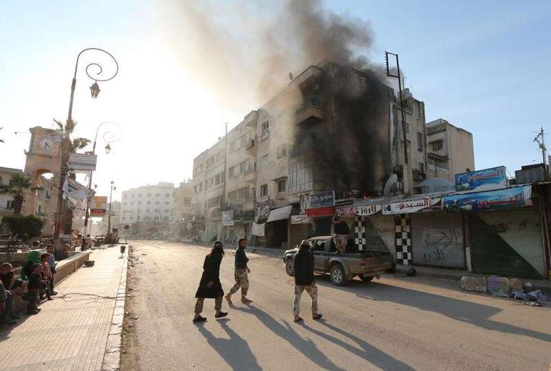 Membros da Frente Al-Nusra, grupo ligado à Al Qaeda, observam incêndio causado por curto-circuito elétrico numa rua em Idlib, na Síria, nesta segunda-feira. 06/04/2015