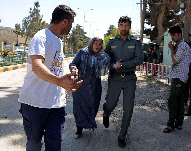 Policial afegão ajuda uma mulher após ataque em Mazar-i-Sharif, no Afeganistão, nesta quinta-feira. 09/04/2015