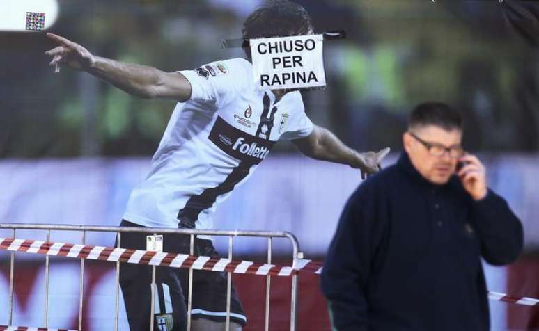 Homem telefona em frente ao pôster de um jogador do Parma, no estádio Ennio Tardini, em Parma, na Itália, em março. 06/03/2015