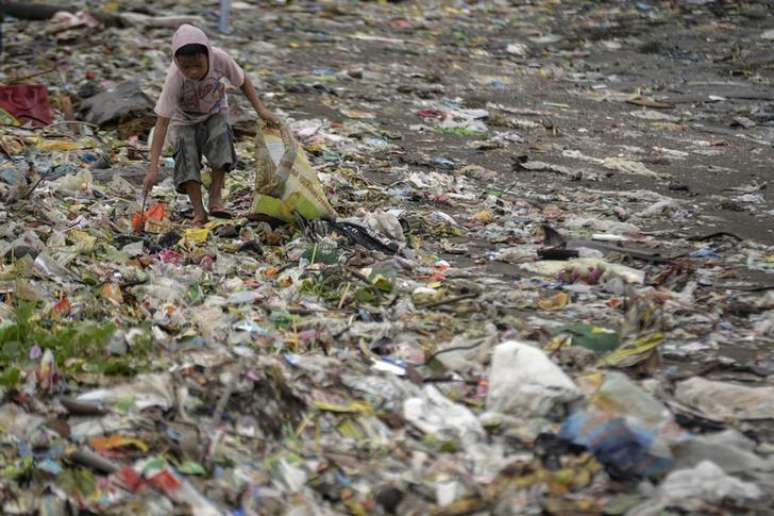 Menino tenta encontrar material reciclável no lixo após a passagem do tufão Hagupit, em Cavite, sul de Manila, nas Filipinas, em dezembro. 09/12/2014