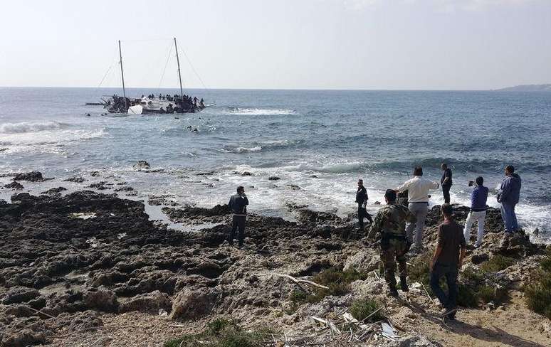 Agentes da guarda costeira grega e locais observam um barco naufragado com imigrantes que tentam chegar à Grécia, perto da ilha de Rodes, nesta segunda-feira. 20/04/2015