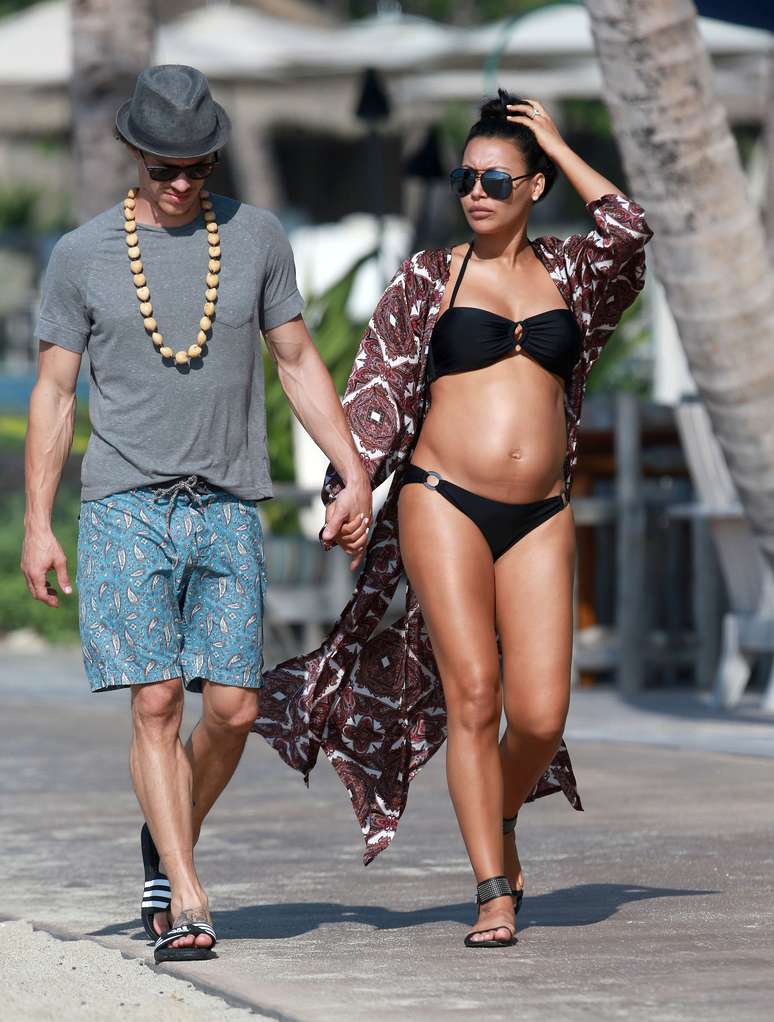 Famosa por viver Santana no seriado Glee, Naya Rivera foi fotografada em uma praia do Havaí com seu marido Ryan Dorsey. A atriz, que está grávida, usou um biquíni preto que mostrou sua barriga.