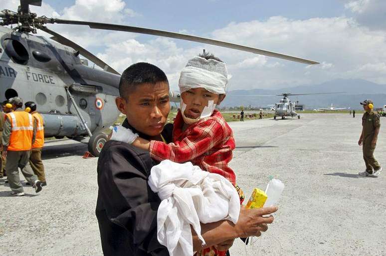 Homem segura uma criança, ferida no terremoto de sábado, depois que soldados indianos os levaram de Trishuli Bazar ao aeroporto em Katmandu, no Nepal, nesta segunda-feira