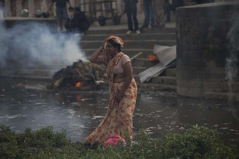 Mulher chora durante o ritual de cremação de uma parente às margens do rio Bagmati em Catmandu, capital do Nepal