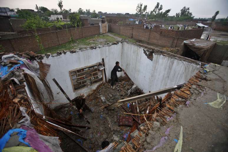 Homens fazem busca em escombros de um casa parcialmente destruída na periferia de Peshawar