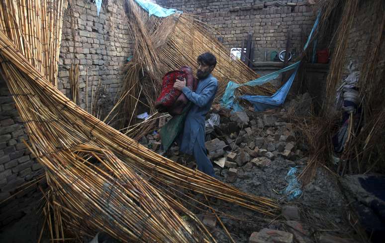 Homem em meio a destroços de sua casa após tempestade, em Peshawar