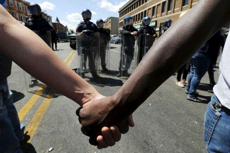 Membros da comunidade dão as mãos em frente a tropas de choque em Baltimore, nos Estados Unidos, nesta terça-feira. 28/04/2015