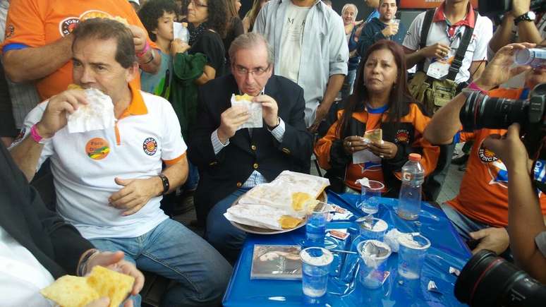 Paulinho da Força e Eduardo Cunha comendo pastel durante evento da Força Sindical