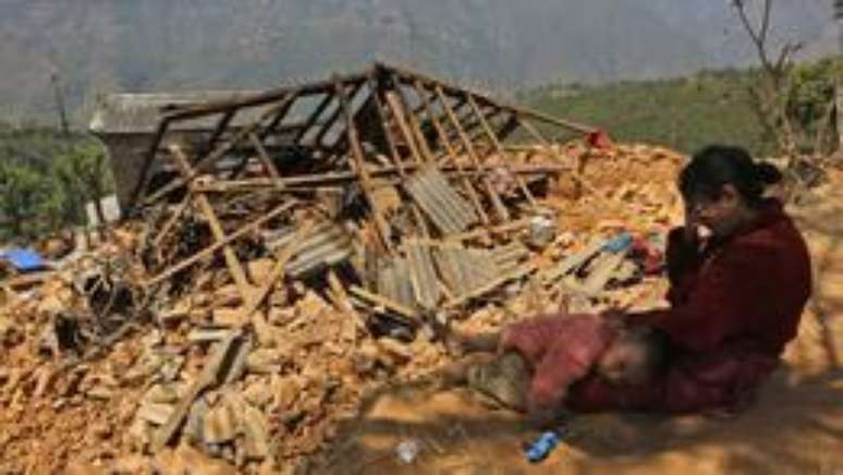 Mulher chora em frente à sua casa destruída (Foto: AP)