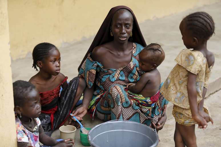 Mulher resgatada por militares nigerianos alimenta seus filhos no acampamento em Malkohi 