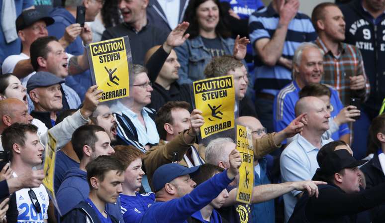 Torcida do Chelsea provoca Gerrard fazendo referência ao escorregão do veterano na derrota ocorrida na última temporada; a partir da falha do meio-campista, o time londrino venceu o duelo por 2 a 0, e o Liverpool viu o Manchester City deslanchar rumo ao título do Inglês 2013/14