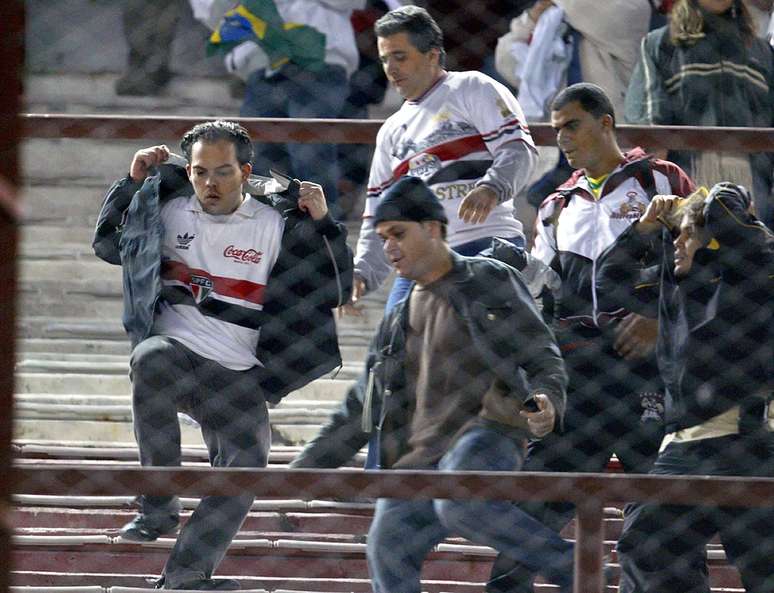 Torcedores do São Paulo deixam a arquibancada do Monumental de Nuñez sob uma chuva de pedradas