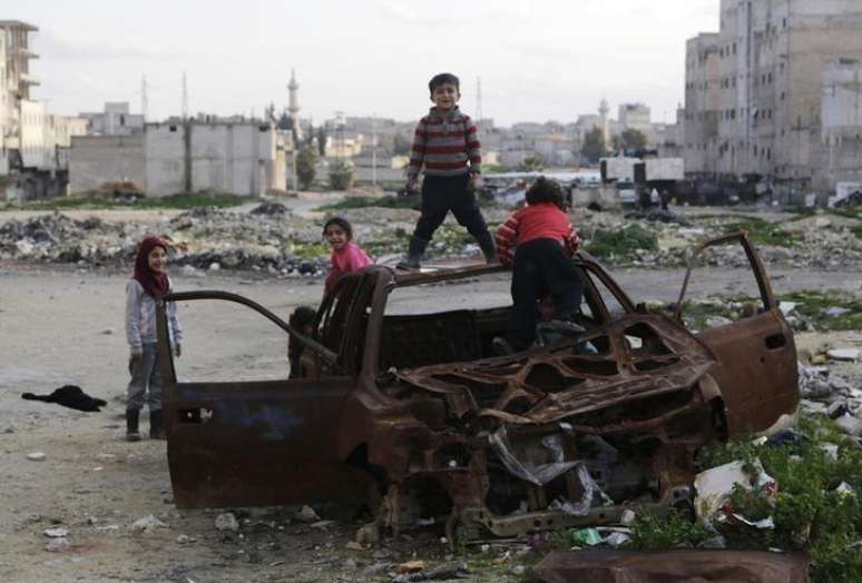 Crianças brincam nos restos de um carro queimado em Aleppo, na Síria, em fevereiro. 16/02/2015