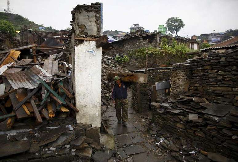 Vítima do terremoto carregando pedaços de madeira nos escombros de uma casa no vilarejo de Barpak.   21/05/2015