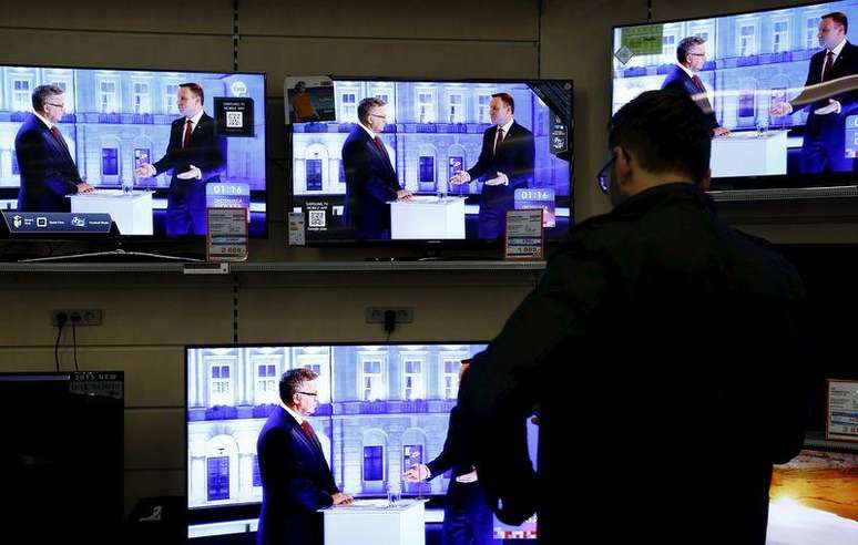 Homem assiste debate entre candidatos a presidente da Polônia em TVs em shopping de Varsóvia. 21/05/2015