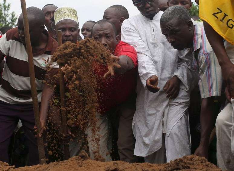 Homem joga terra sobre o corpo de líder oposicionista Zedi Feruzi durante seu enterro em Bujumbura. 24/05/2015