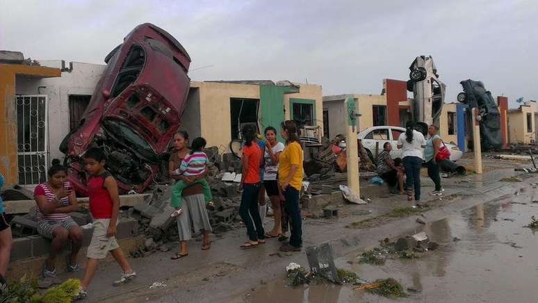 Moradores saem à rua, enquanto carros arrastados por um tornado são vistos numa rua em Ciudad Acuna, no México, nesta segunda-feira. 25/05/2015