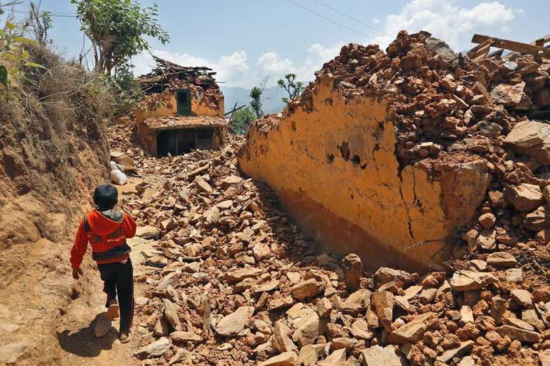 Menino nepalês anda entre destroços de casas destruídas no terremoto de 25 de abril na vila Pauwathok, distrito Sindhupalchok, Nepal