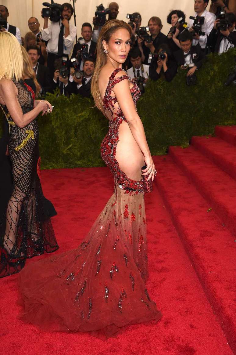 Jennifer Lopez apostou em vestido Versace, cujo desenho de dragão vermelho sobre fundo nude não cobriu as laterais do quadril, dando a impressão de ser bem maior do que é