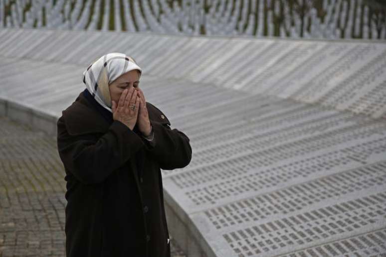 Fadila Efendic, que perdeu o filho e o marido no massacre de Srebrenica, reza ao lado das placas com nomes das vítimas do genocídio no memorial de Potocari, em Srebrenica, na Bósnia, em março. 18/03/2015