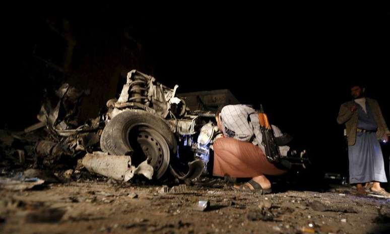 Homem observa carro em local de explosão de carro-bomba na capital do Iêmen, Sanaa.  17/6/2015.