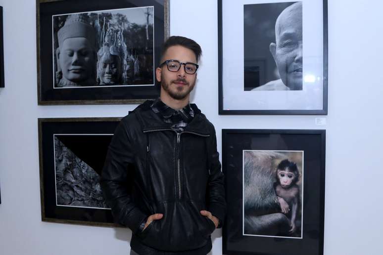 O cantor J&uacute;nior Lima posa ao lado de suas fotografias, da exposi&ccedil;&atilde;o "Faces", na galeria Matilha Cultural, na regi&atilde;o central de S&atilde;o Paulo, nesta ter&ccedil;a-feira (16)