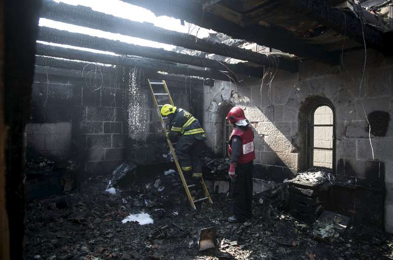 Bombeiros israelenses trabalham em meio aos destroços causados por um incêndio na igreja onde Jesus Cristo fez o milagre da multiplicação de pães e peixes
