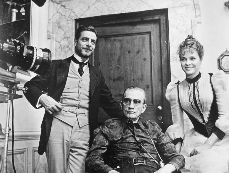 O diretor Luchino Visconti (sentado) com os atores Giancarlo Giannini e Laura Antonelli no set de filmagem do filme &#034;O Inocente&#034;, em Roma, em janeiro de 1976