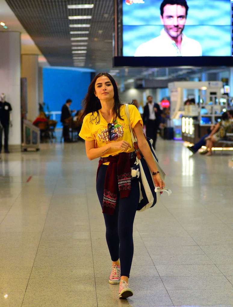 Maria Casadevall quase nunca combina as peças que usa. Dessa vez não foi diferente: legging preta, camisa amarela, com estampa, tênis rosa, blusa de lã com estampa nas mangas e bolsa listrada. De tudo um pouco e informação demais.