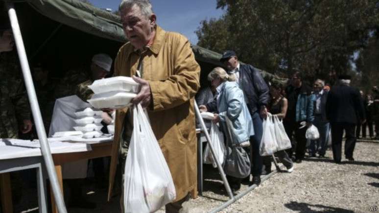 Refeições gratuitas sendo distribuídas em Atenas; desemprego está em alta e há pressão para redução nas aposentadorias