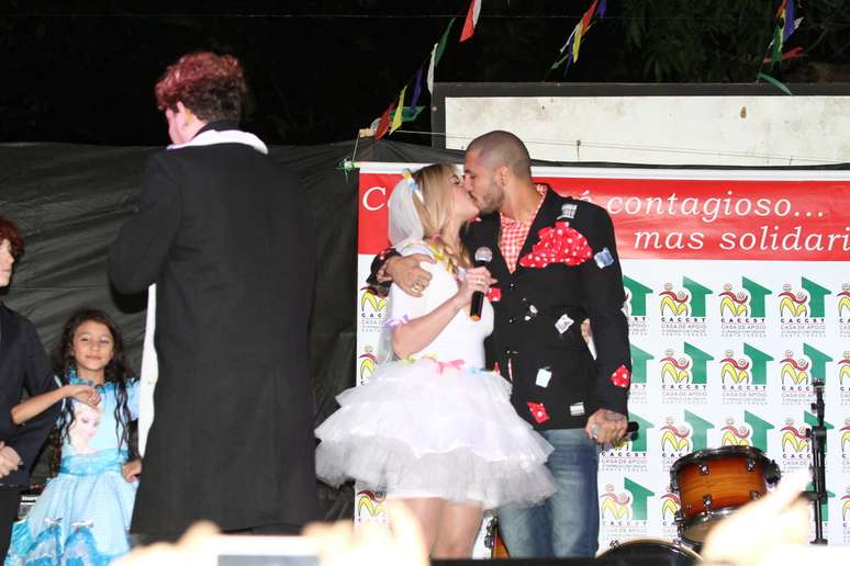 O casal Fernando e Aline, ex-BBBs, se beija durante festa junina beneficente, na noite deste sábado (27)