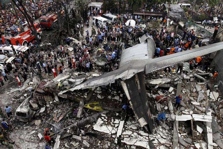 Forças de segurança examinando os destroços da aeronave C-130 Hercules, na cidade de Medan, na Indonésia.    30/06/2015