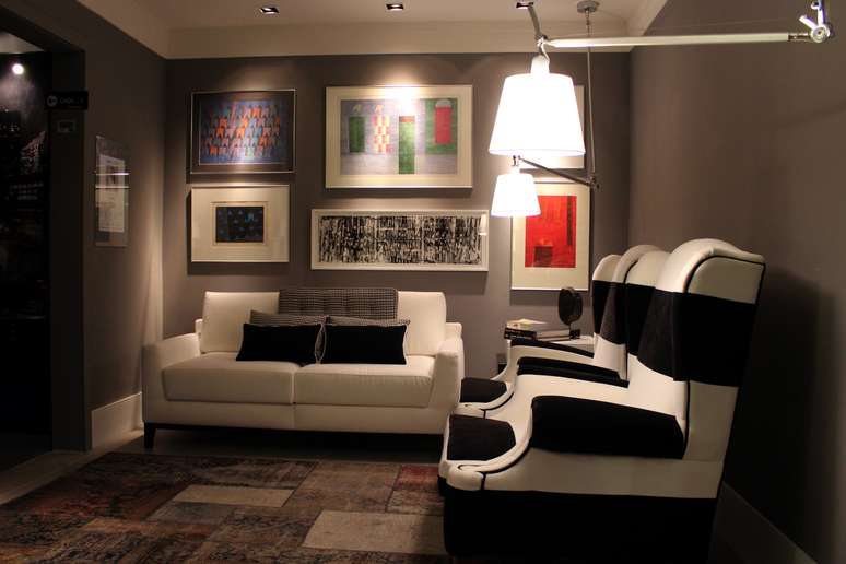 Tom escuro das paredes destaca as obras de arte e os móveis do Gabinete de Paula Lino