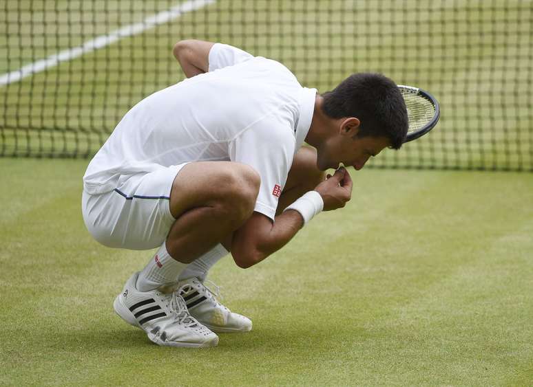Djokovic come a grama de Wimbledon para festejar sua vit&oacute;ria