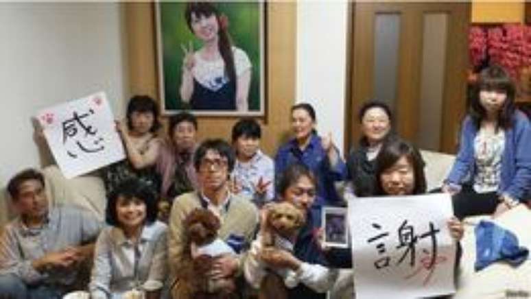 Yasuo Takamatsu (à esquerda), Masaaki Narita (centro) e sua esposa Hiromi junto com outras família reunidos em frente ao retrado de Emi