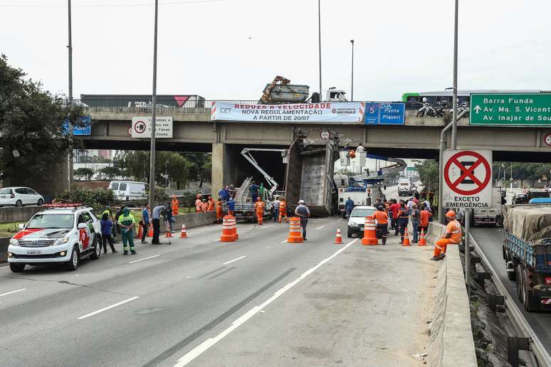 Homens da Defesa Civil tentam cortar caçamba de caminhão que bateu na Ponte do Piqueri; a Marginal Tietê, sentido Ayrton Sena, está interditada na via onde houve o acidente