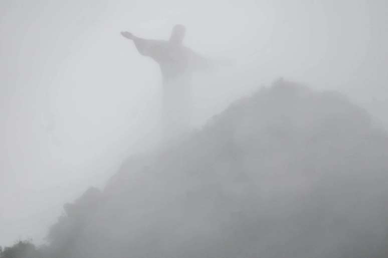 Cristo Redentor visto de Botafogo, Zona Sul do Rio de Janeiro (RJ), no amanhecer com céu nublado e chuva.