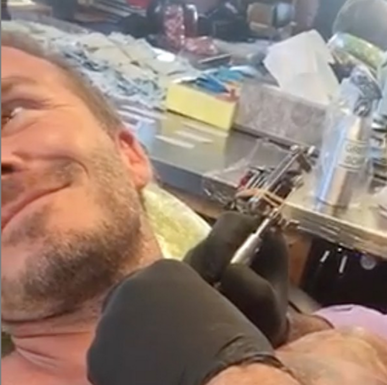 David Beckham fazendo uma de suas várias tatuagens