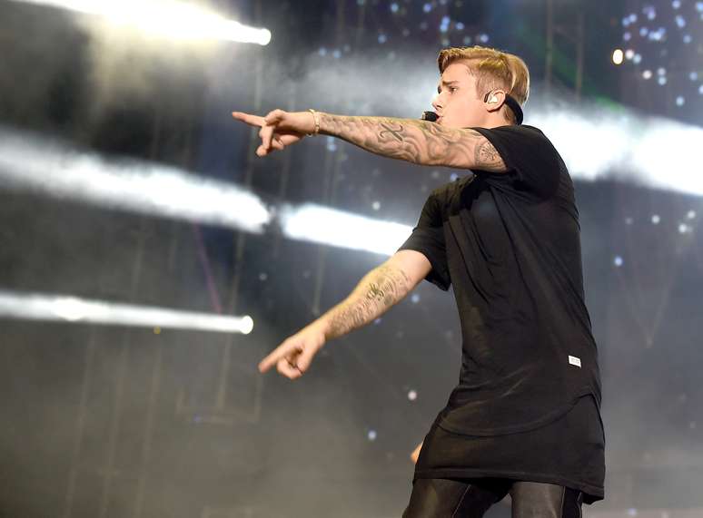Justin Bieber usa look todo preto para show com camisetas alongadas. Veja como a de cima traz a barra arredondada, para enfatizar a sobreposição das peças