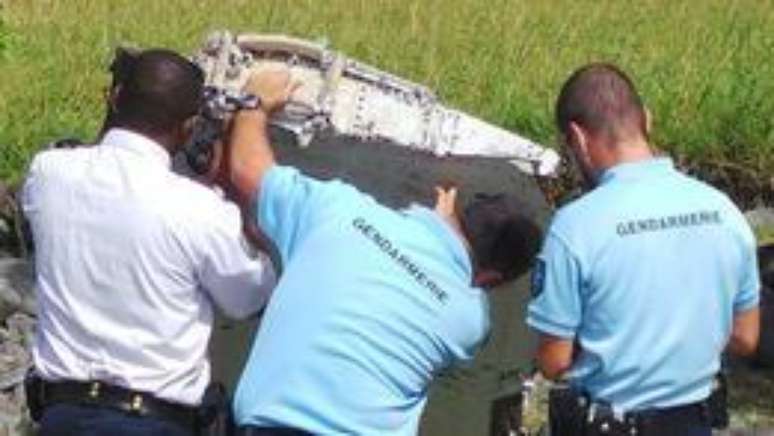 Policiais da ilha Reunião examinam o fragmento da asa do Boeing 777.