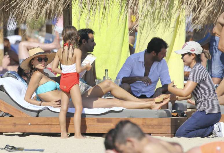 Alessandra Ambrósio recebe massagem no pé e fala com a filha  Anja Louise, em praia da Grécia, nesta quarta-feira (12)
